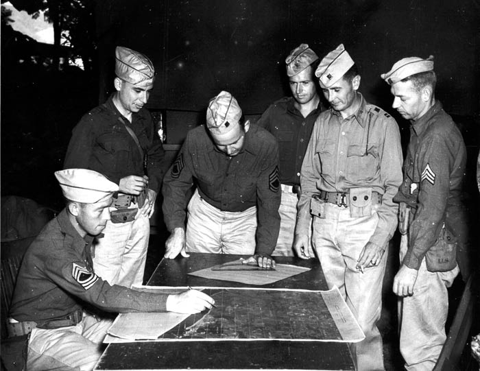 Somewhere in a forest in Puerto Rico, Master Sgt. Sparks, 1st Lt. Cohan, Tech. Sgt. Habor, 1st Lt. Soully, Capt. Wentsworth and Sgt. Vassewr of the 25th Field Artillery work hard on a five direction center. Caguas, Puerto Rico. November 1941.  SC 126166